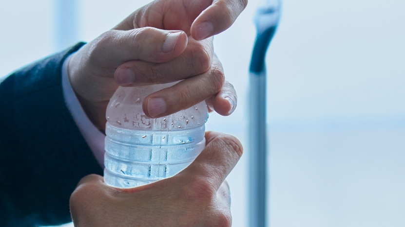 A person opens a sealed plastic water bottle at an airport
