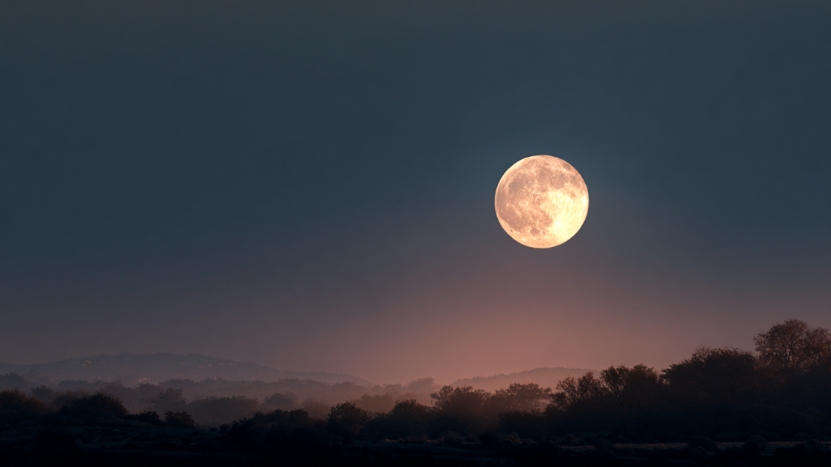 Full moon rises over a quiet landscape, hinting at how the moon affects your sleep