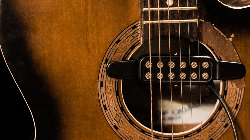 Close-up of an acoustic guitar with a magnetic soundhole pickup installed and cable connected for amplification