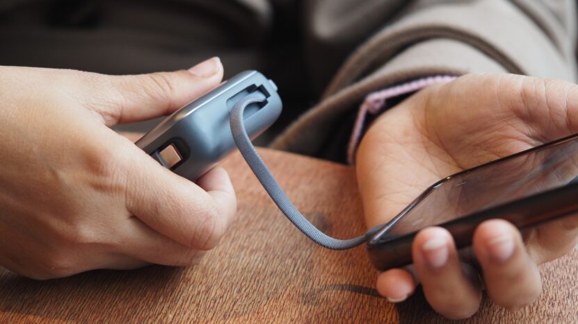 A person charges a phone with a portable power bank during travel