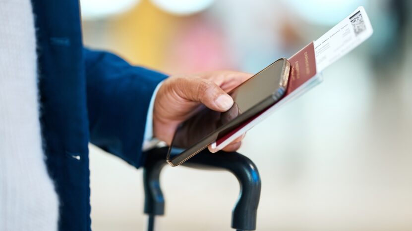 A traveler holds a passport, phone, and flight ticket at the airport